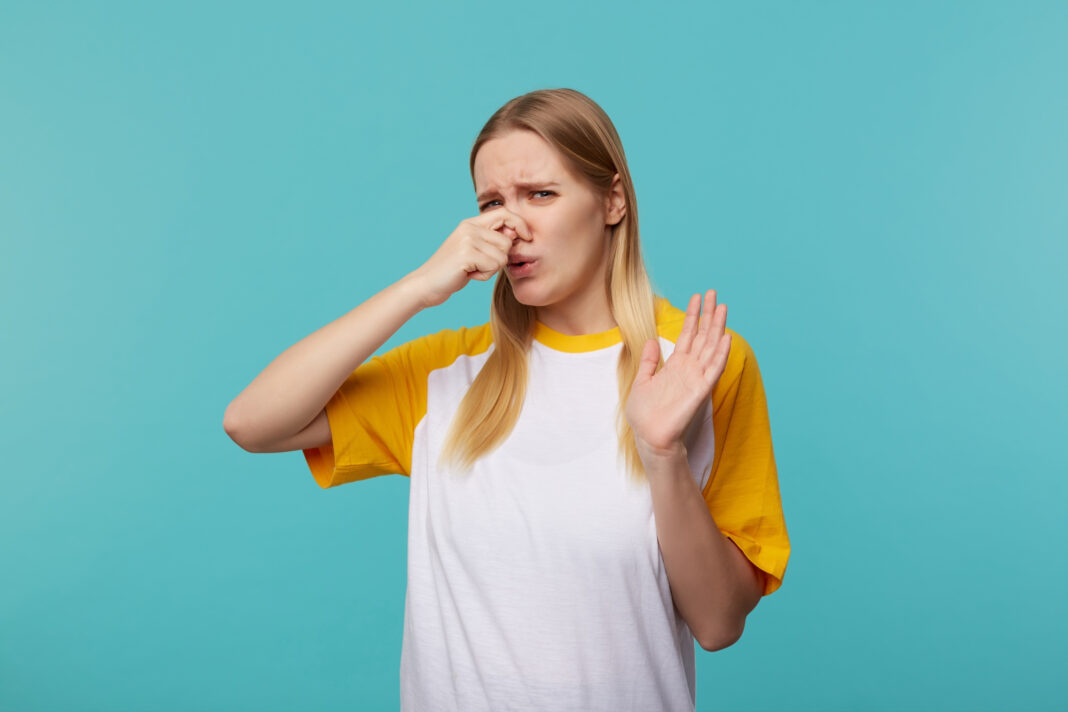 displeased-young-attractive-long-haired-blonde-female-closing-her-nose-with-raised-hand-frowning-face-while-feeling-bad-smell-posing-blue-background0